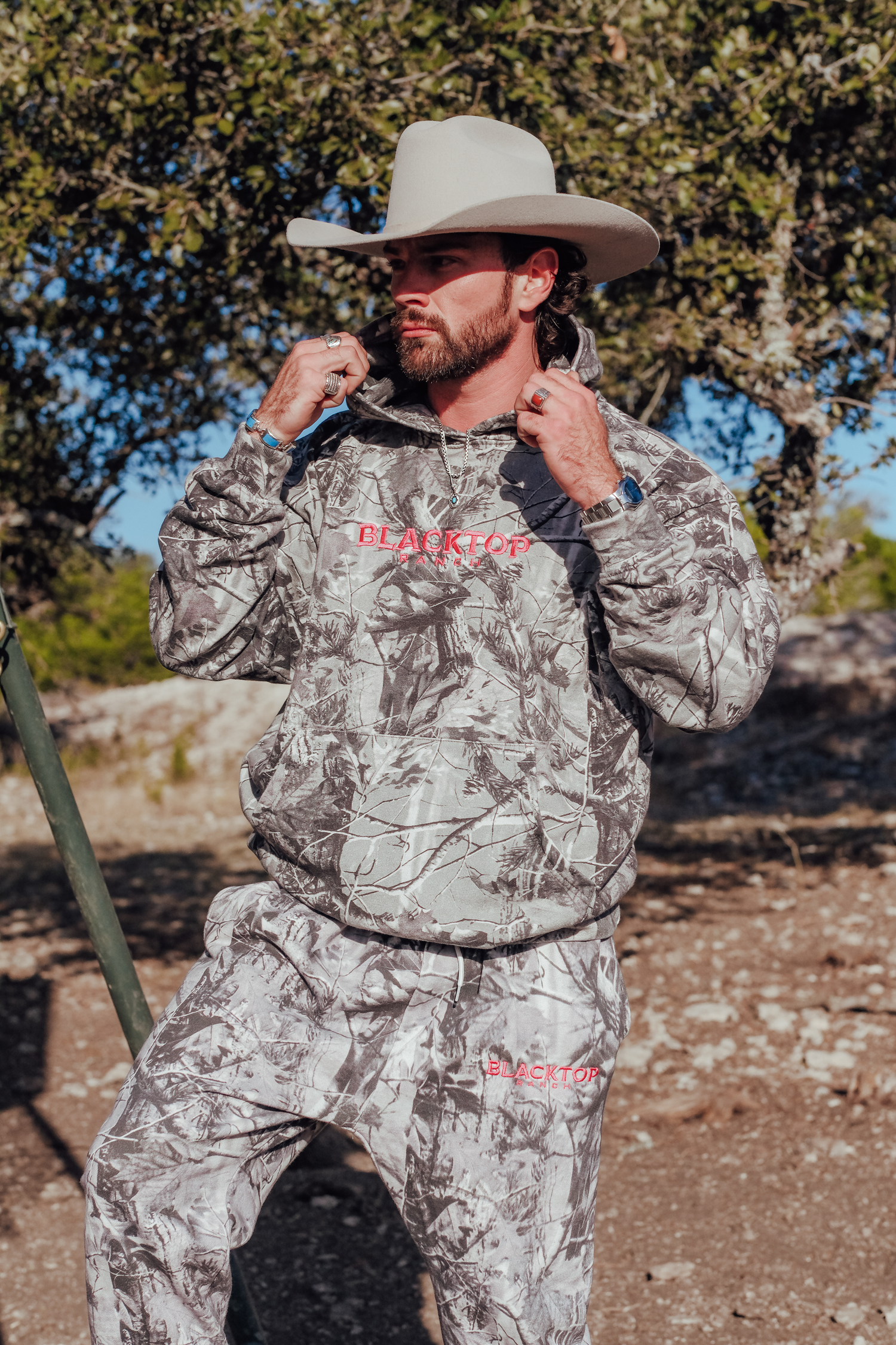 Oversized camo hoodie by Blacktop Ranch worn in outdoor western fashion setting
