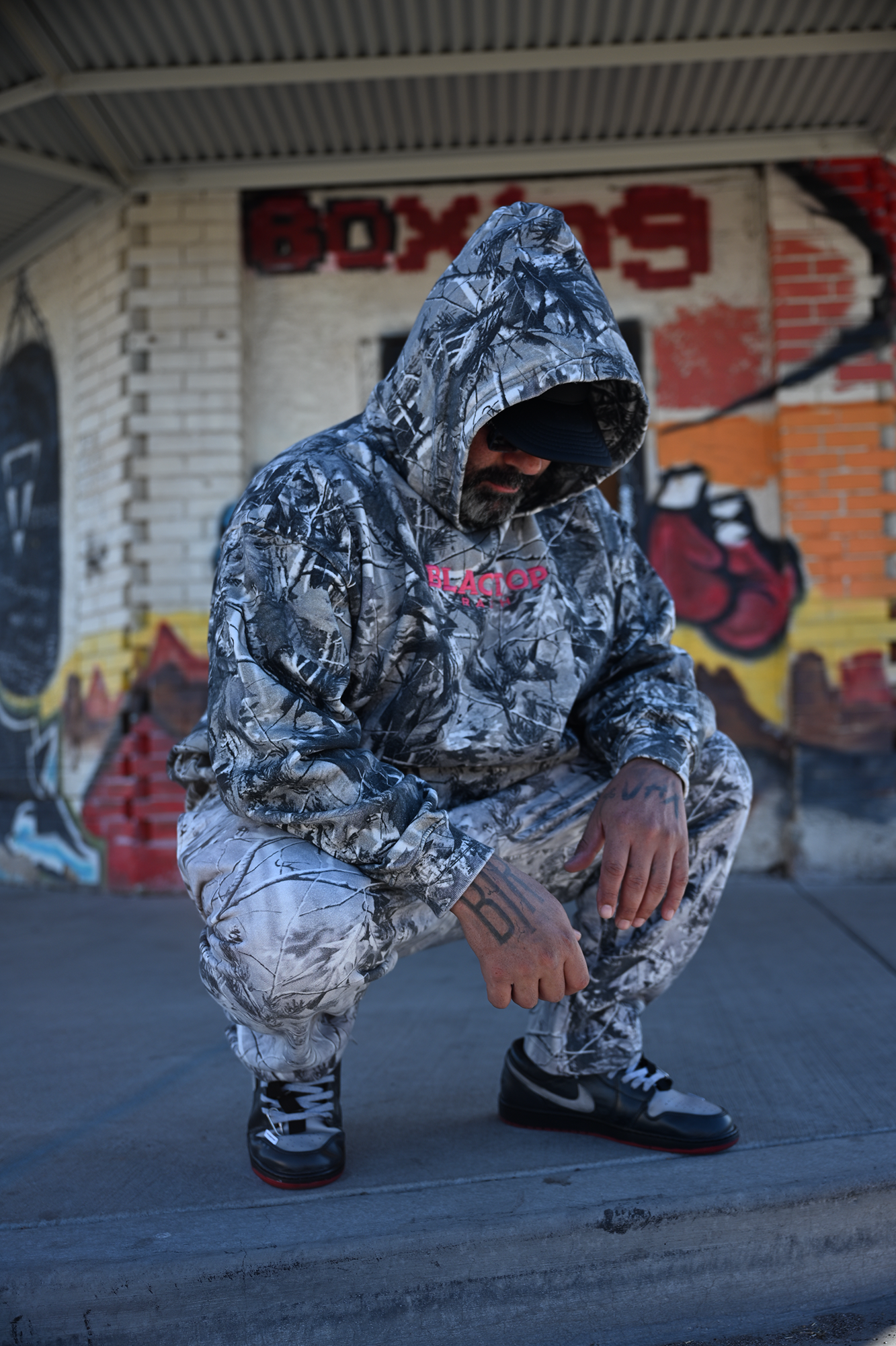 Oversized camo hoodie by Blacktop Ranch worn in urban fashion setting